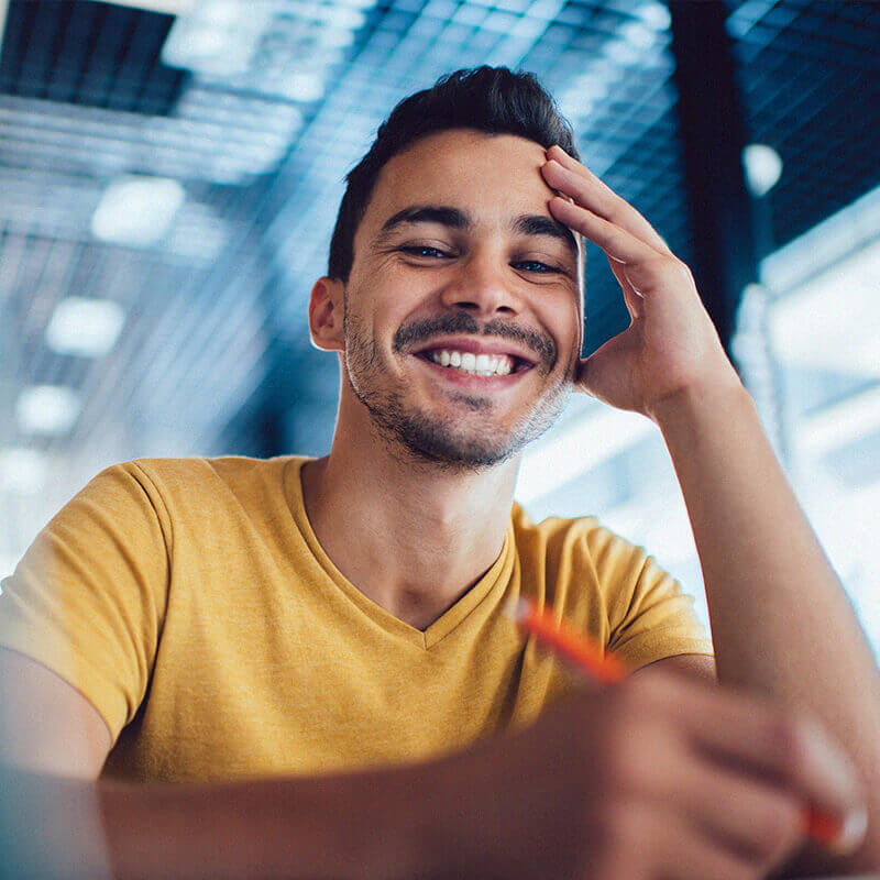 man writing and smiling at camera