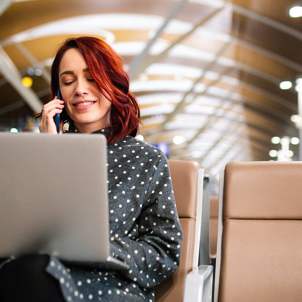 woman in airport on phone and laptop